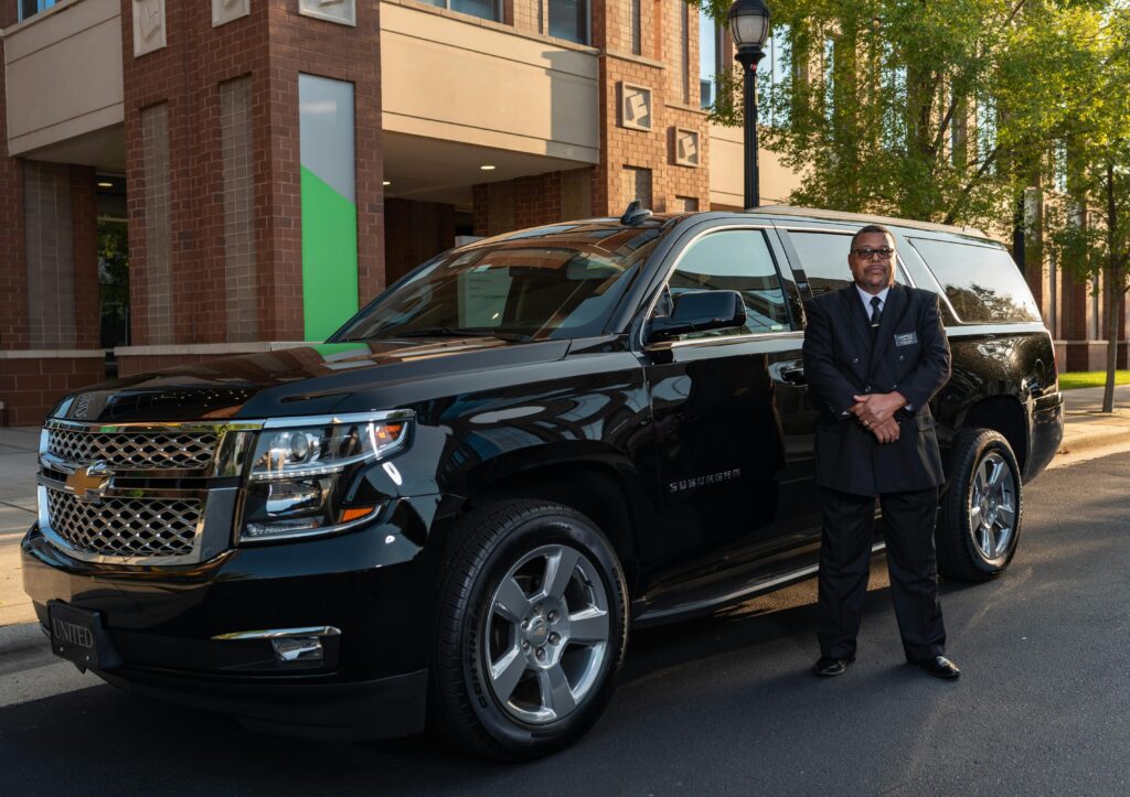 Chauffeur Standing by Luxury Black SUV Outdoors
